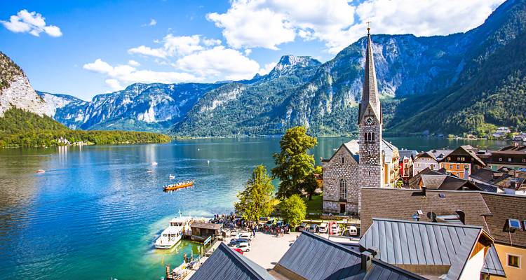 Scenic view of Hallstatt with a church, lake, and lush mountains.