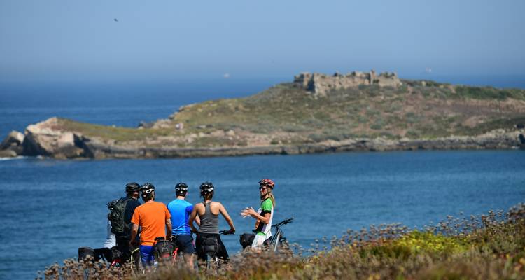 Cyclists resting with a scenic coastal view.