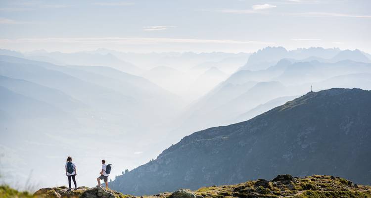 Wandelaars op een schilderachtig bergpad met mistige bergen in de verte.