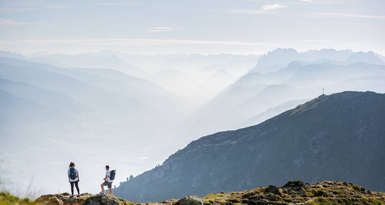 Randonneurs à un belvédère de montagne avec de la brume couvrant les sommets distants.