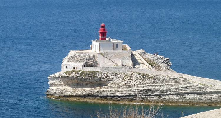 Phare sur une falaise rocheuse entouré par un océan bleu.