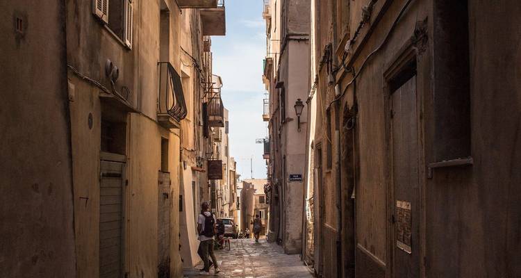 Rue étroite dans une ville européenne historique avec des gens qui marchent.