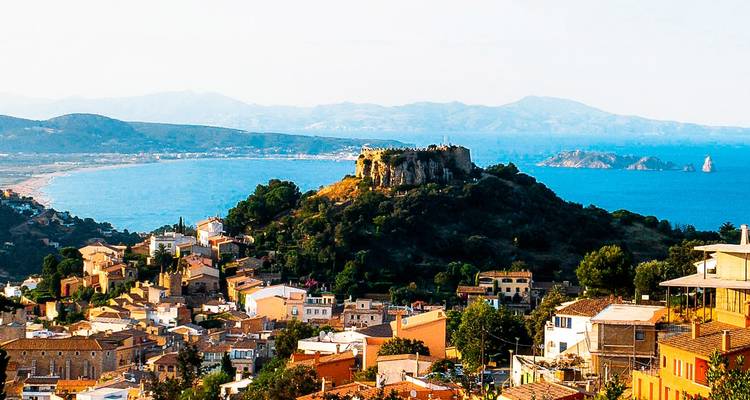 Vista aérea de un pueblo costero con un castillo en ruinas en una colina.