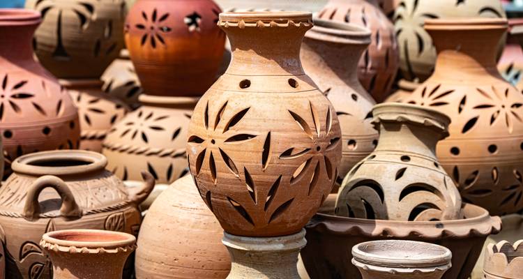 Verschillende kleipotten tentoongesteld in een buitenomgeving.