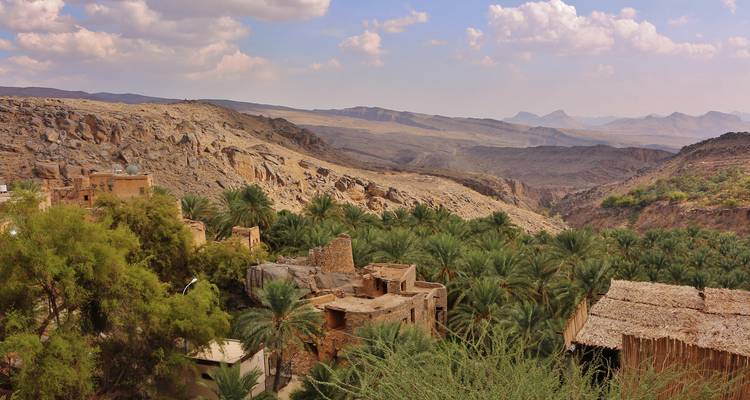 Weelderige oase in een rotsachtige vallei met traditionele gebouwen.