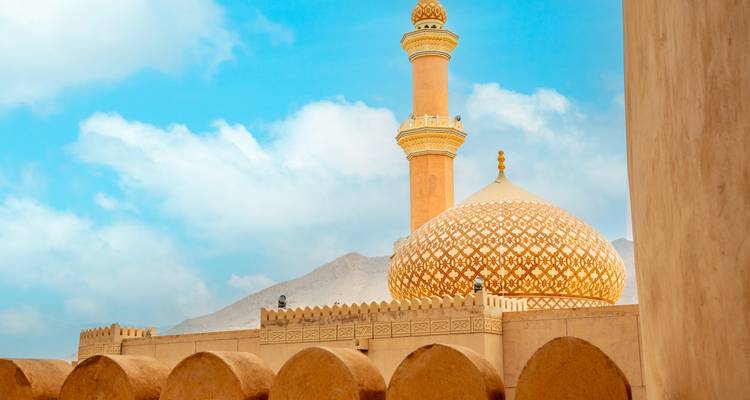 Une mosquée avec un dôme et un minaret sous un ciel bleu.