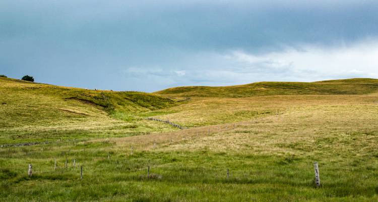 Rolling hills and open fields under a cloudy sky.