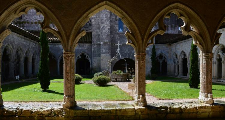 Intérieur d'un cloître historique avec arcades et verdure.
