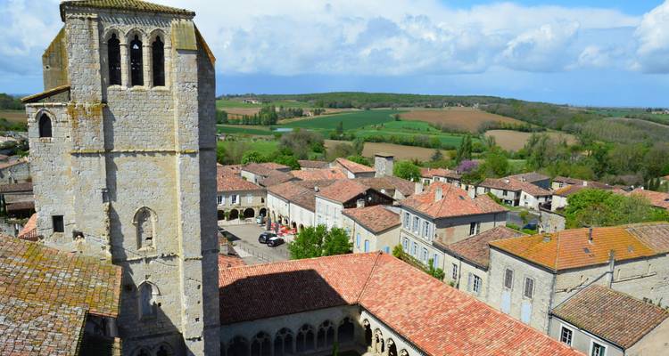 Un village historique avec un clocher d'église, vue aérienne avec la campagne en arrière-plan.