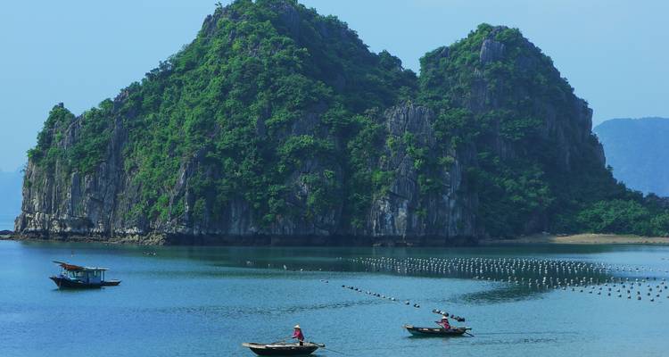 Limestone karsts rising from a tranquil bay.