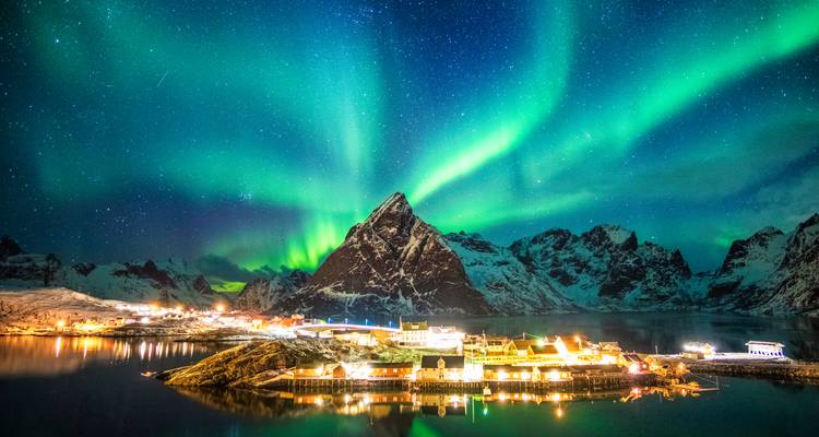 Nordlichter über einem Berg und Dorf in Lofoten.