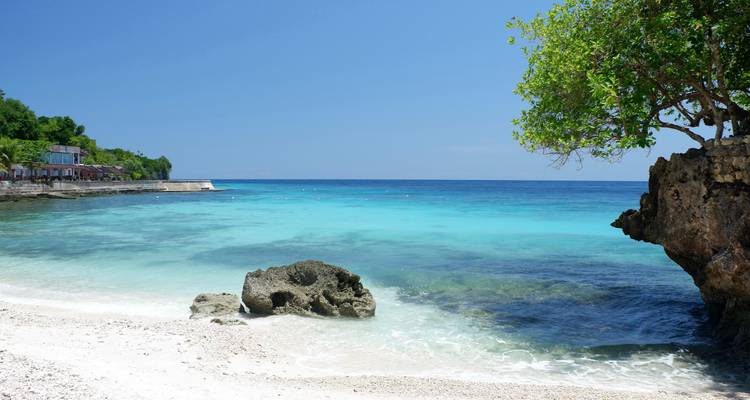 Vue côtière pittoresque avec un ciel bleu clair et un océan turquoise.