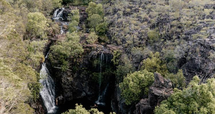 Waterfalls surrounded by rocky terrain and greenery.