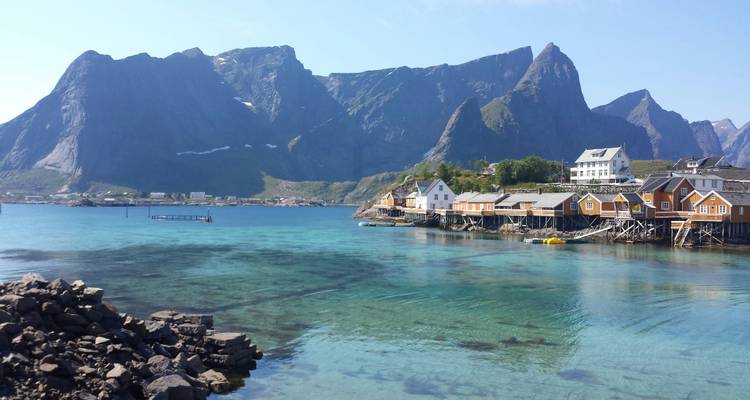 Colorful houses near clear blue ocean with mountains.