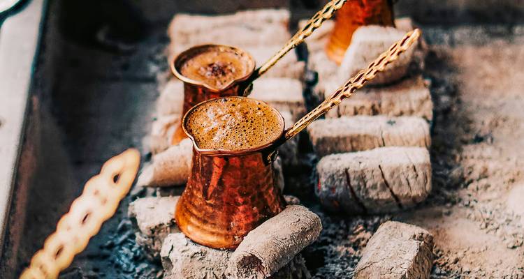 Copper pots with coffee on a fire.