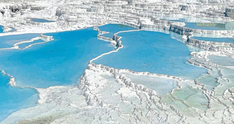 Natural terraces with turquoise water and white mineral deposits.