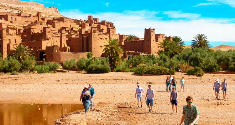 People walking in front of a fortified clay village.