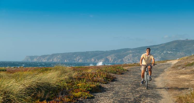Person cycling along a coastal path with cliffs in the distance.