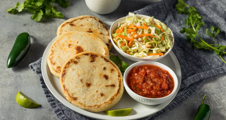 Plate of pupusas with salsa and cabbage salad.