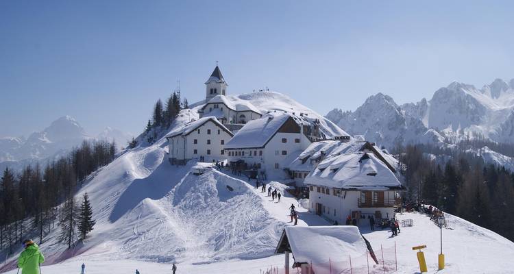 Retraite de montagne enneigée avec un chalet de ski et des personnes qui skient.