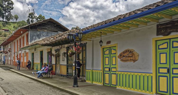 Mensen die buiten zitten voor een rij kleurrijke koloniale gebouwen.