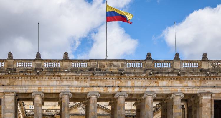 Neoklassiek gebouw met Colombiaanse vlag onder een blauwe hemel.