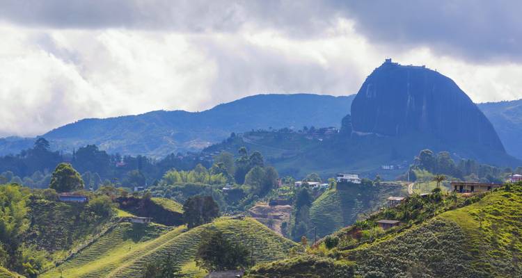 Landschap met hoge rotsachtige heuvel onder wolken.