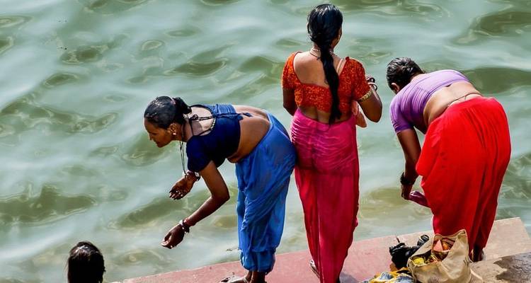 Femmes en sari traditionnel lavant au bord de la rivière.