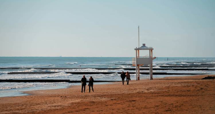 Strand met een reddingspost en wandelende mensen.