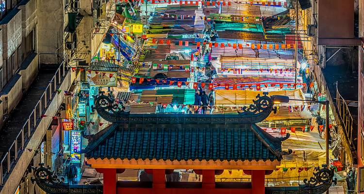 A bustling nighttime market with colorful lights and stalls.