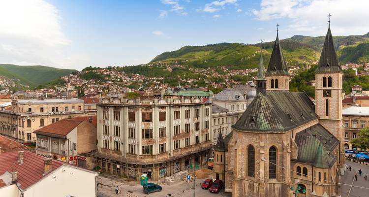 Vue panoramique d'une ville avec une église et des collines verdoyantes.