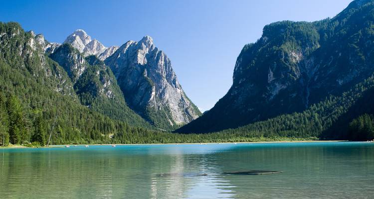 Pintoresco lago rodeado de montañas bajo un cielo azul.