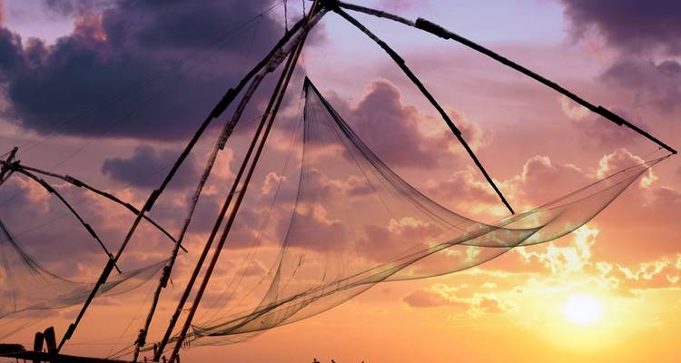 Silhouettes de filets de pêche chinois contre un ciel de coucher de soleil coloré au-dessus de la mer d'Arabie au Kerala.