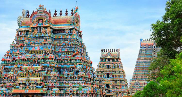 Des tours colorées et finement sculptées de style temple Meenakshi se dressant contre un ciel bleu.
