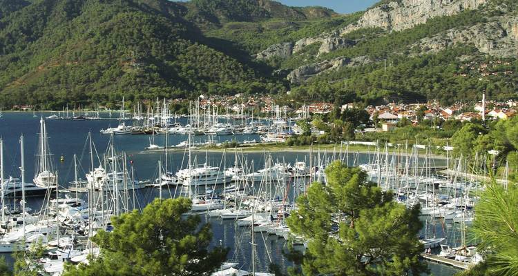 Marina omgeven door bomen in Göcek met rotsachtige bergen en tal van zeilboten.