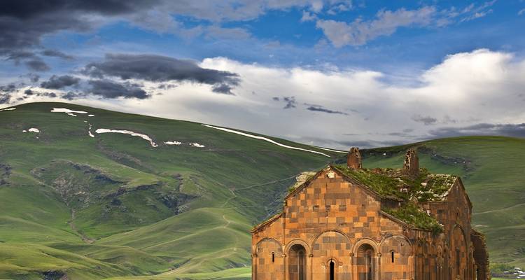 Ruines d'une ancienne cathédrale dans une vallée verdoyante.