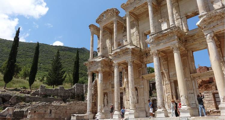 Los visitantes explorando las columnas de mármol de la Biblioteca de Celso de Éfeso bajo un cielo azul