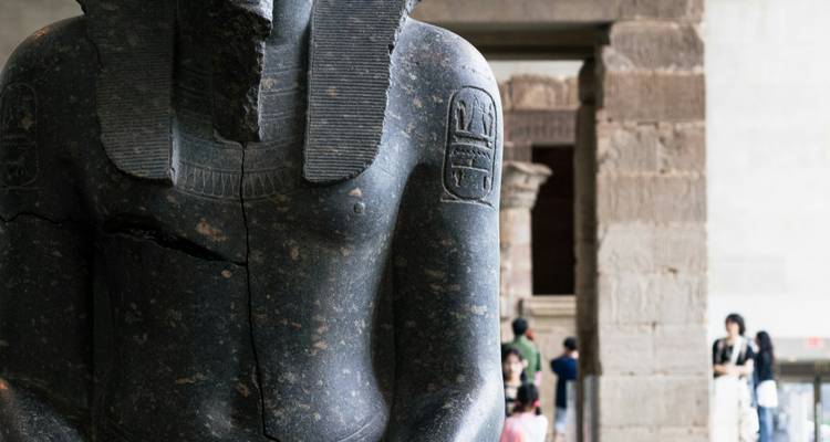 Une statue de pierre avec des hiéroglyphes dans un cadre muséal.