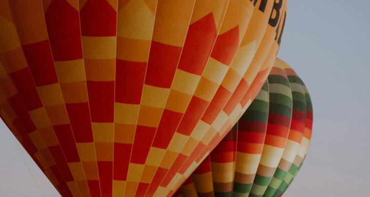 Primer plano de globos aerostáticos coloridos superpuestos contra un cielo despejado.