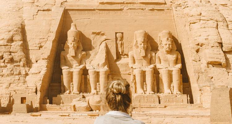 Una persona mirando los templos de Abu Simbel en el desierto egipcio.