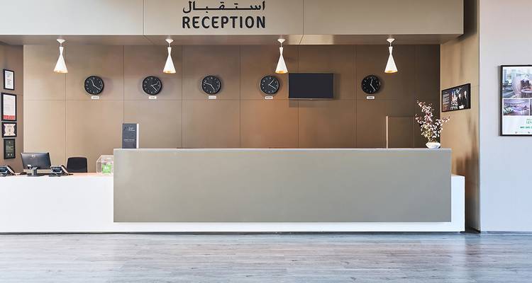 Zone de réception d'hôtel élégante avec des horloges affichant différents fuseaux horaires.