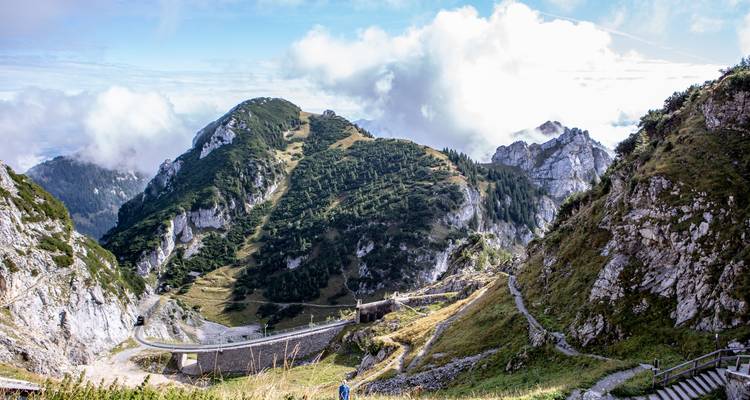 Paisaje montañoso escénico con senderos para caminar y nubes.