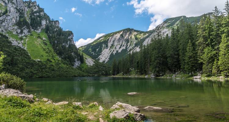 Lago verde rodeado de acantilados rocosos y árboles.