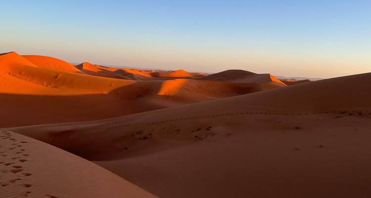 Uitgestrekte woestijnduinen bij zonsondergang.