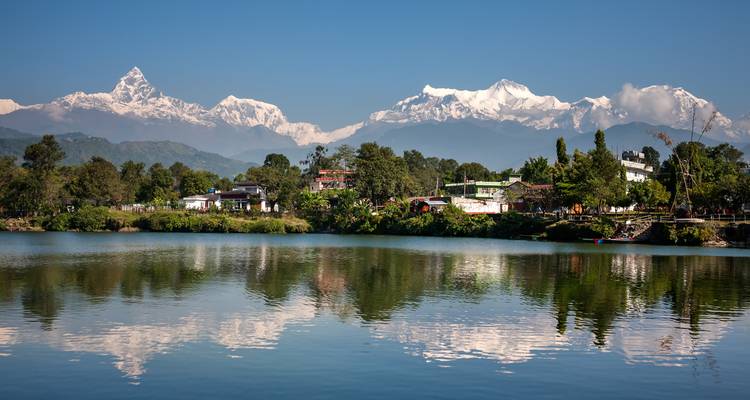 Reflet de montagnes et de bâtiments sur un lac.