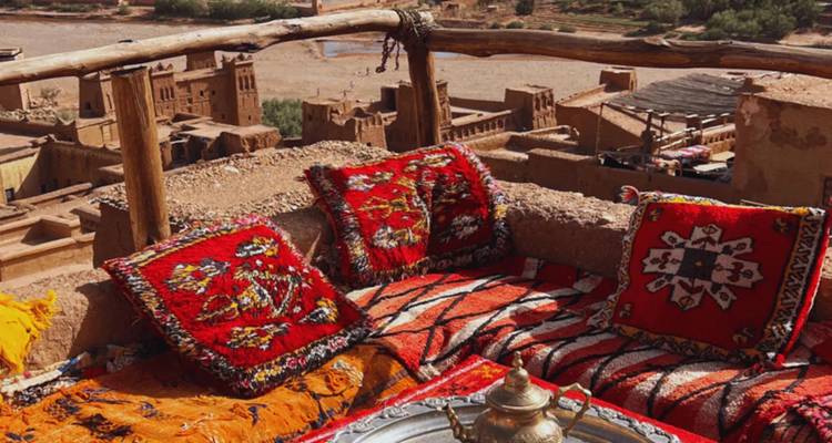 Moroccan rooftop terrace with colorful cushions and teapot.