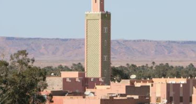 Un paysage urbain avec un minaret de mosquée et un arrière-plan désertique.