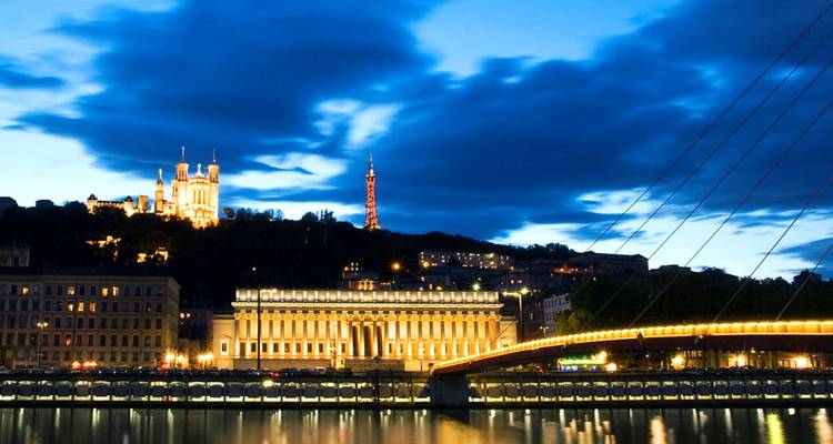 Pont avec ville illuminée et basilique la nuit.