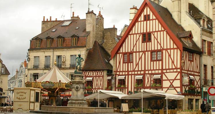 Statue et bâtiments médiévaux sur une place historique.