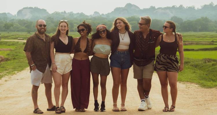 Groupe de personnes debout ensemble sur un chemin de terre avec de la verdure autour.